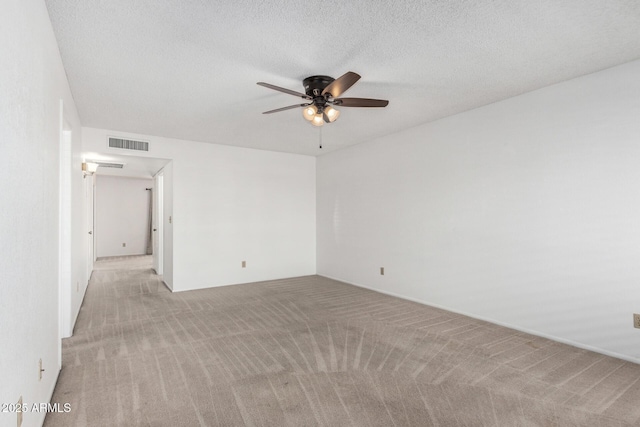 spare room featuring light carpet, a textured ceiling, and ceiling fan