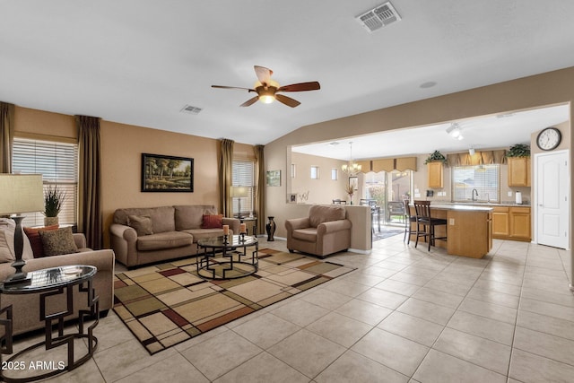 tiled living room with lofted ceiling, sink, and ceiling fan with notable chandelier