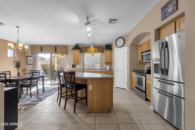 kitchen featuring sink, appliances with stainless steel finishes, hanging light fixtures, a kitchen island, and light tile patterned flooring