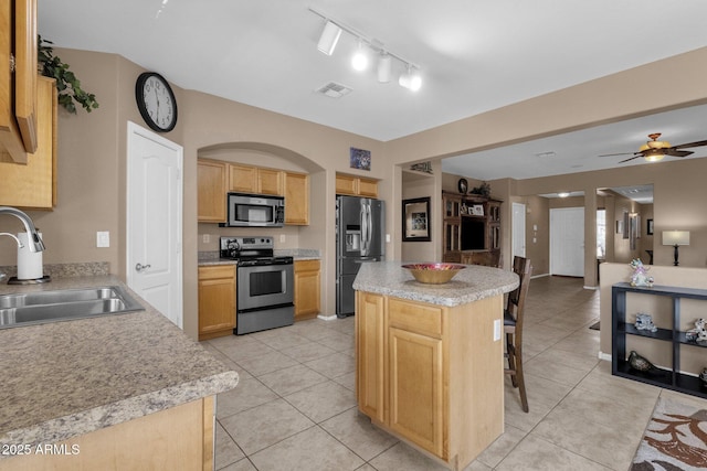 kitchen featuring sink, stainless steel appliances, a center island, and light tile patterned flooring