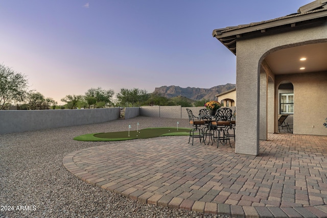 4126 S Last Chance Trl, Gold Canyon, AZ 85118 - view of patio with an area to practice putting, a fenced backyard, a mountain view, and outdoor dining area