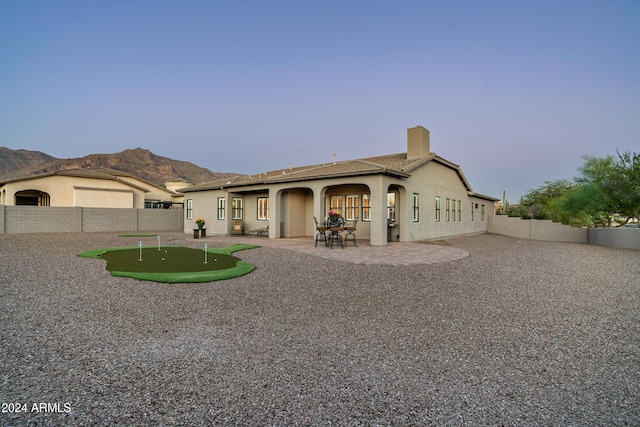 4126 S Last Chance Trl, Gold Canyon, AZ 85118 - view of front facade with an area to practice putting, a chimney, a fenced backyard, a patio area, and stucco siding