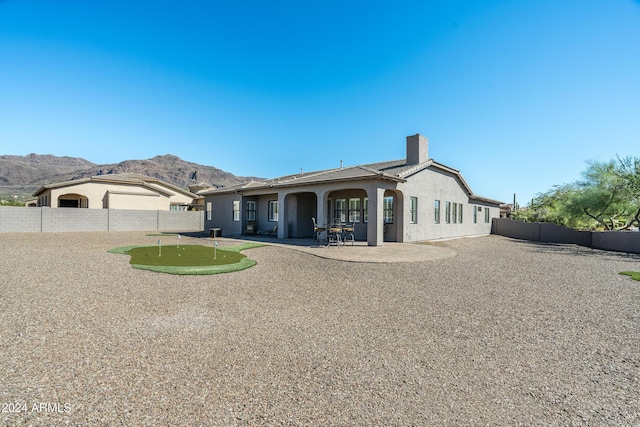 4126 S Last Chance Trl, Gold Canyon, AZ 85118 - view of front of house featuring a putting area, a mountain view, a fenced backyard, a patio area, and a chimney
