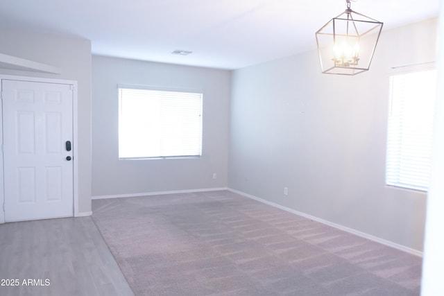 unfurnished room with a chandelier and carpet