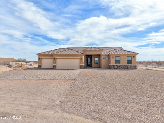 view of front of property with an attached garage, stone siding, fence, and stucco siding