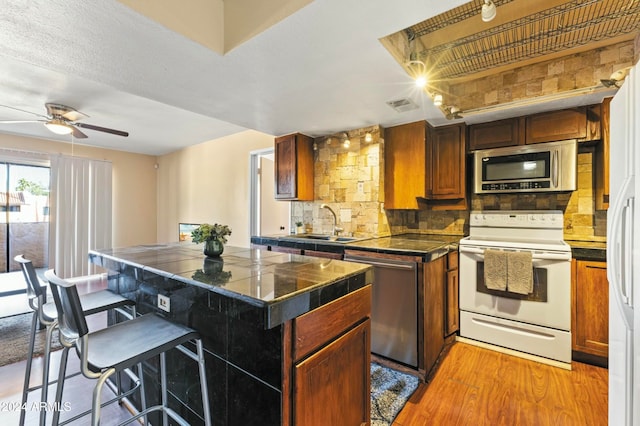 kitchen featuring a center island, backsplash, sink, light hardwood / wood-style flooring, and appliances with stainless steel finishes