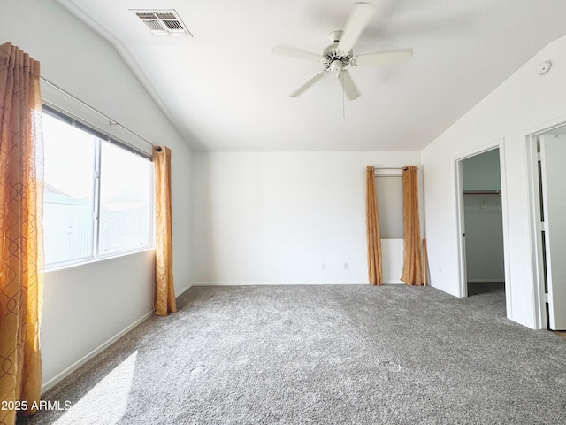 unfurnished bedroom featuring a spacious closet, visible vents, carpet floors, and lofted ceiling