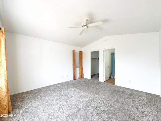 unfurnished bedroom with ceiling fan, a closet, a spacious closet, vaulted ceiling, and carpet flooring