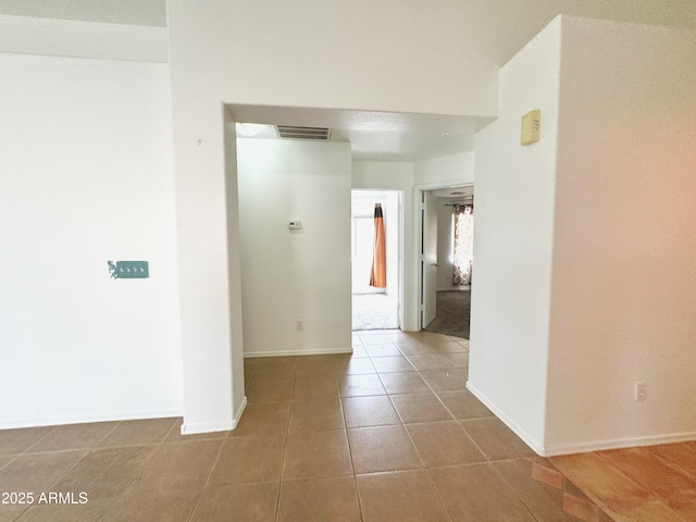 corridor featuring baseboards, tile patterned flooring, and visible vents