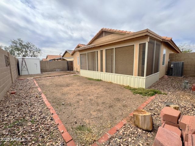 view of property exterior with a sunroom, an outbuilding, and a fenced backyard