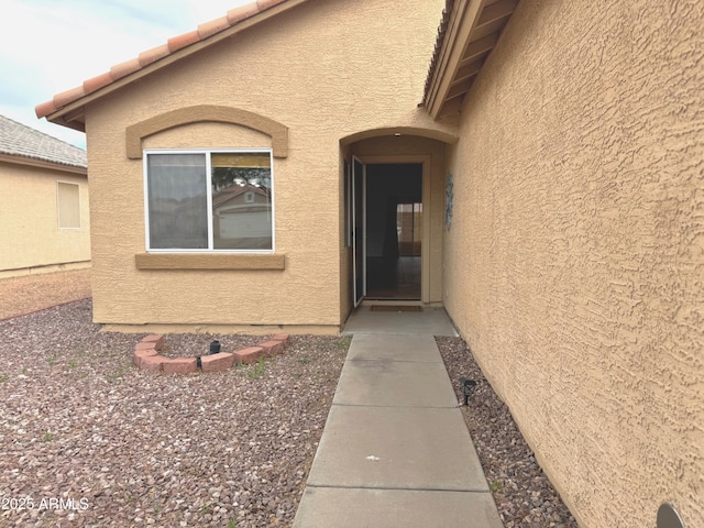 doorway to property with stucco siding and a tiled roof