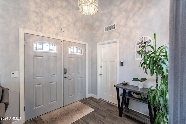 entrance foyer with dark wood-type flooring, a towering ceiling, and visible vents