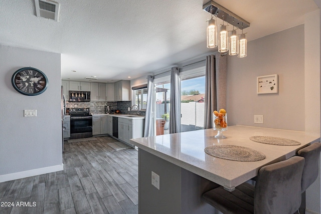 kitchen with stainless steel appliances, a peninsula, a sink, visible vents, and gray cabinets