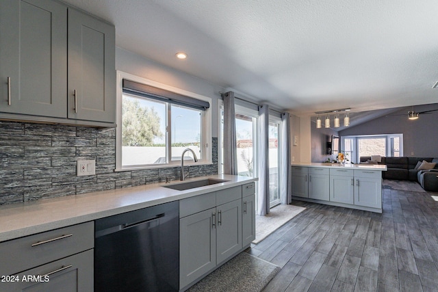 kitchen with tasteful backsplash, gray cabinetry, open floor plan, a sink, and dishwashing machine