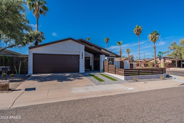 view of front of house with a garage, driveway, a fenced front yard, and stucco siding