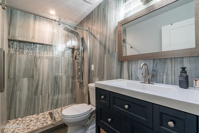 bathroom with tile walls, backsplash, toilet, a shower stall, and vanity