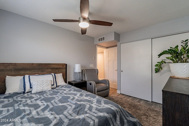 bedroom featuring a ceiling fan, visible vents, and wood finished floors