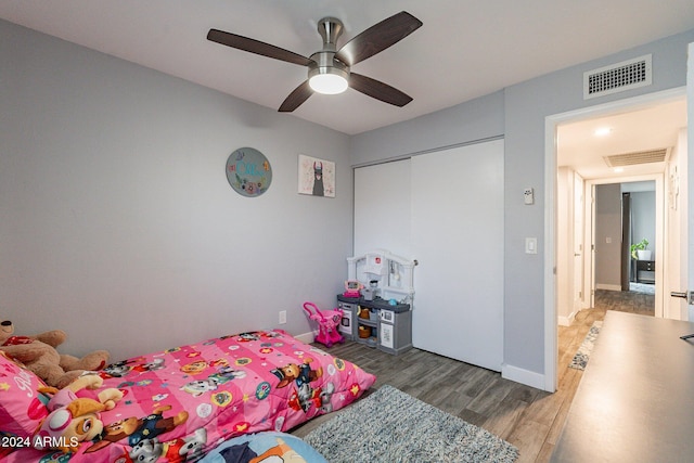 bedroom featuring baseboards, visible vents, a ceiling fan, wood finished floors, and a closet