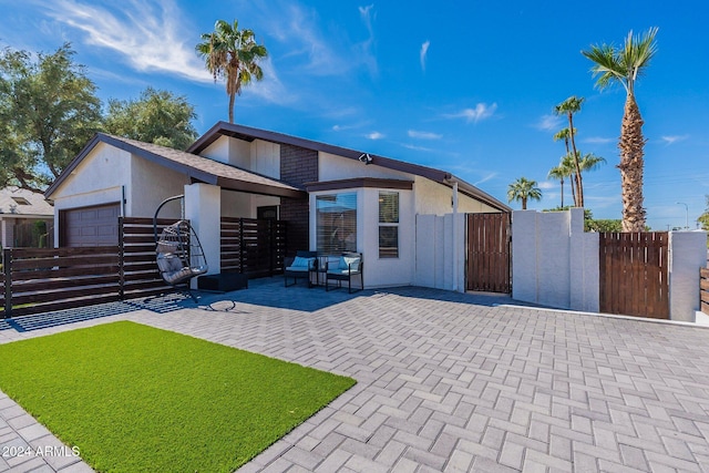 view of front facade with a garage, fence, a gate, and stucco siding