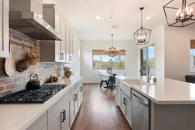 kitchen with gas cooktop, stainless steel dishwasher, wall chimney exhaust hood, sink, and a center island with sink