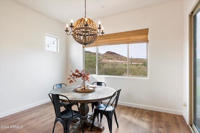 dining room with hardwood / wood-style floors, a mountain view, and an inviting chandelier