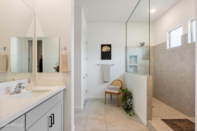 bathroom with tile patterned flooring, vanity, and tiled shower