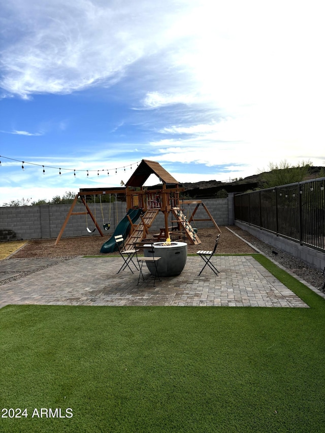 view of playground featuring a patio area and a lawn