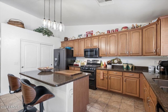 kitchen with hanging light fixtures, a kitchen island, lofted ceiling, light tile patterned floors, and black appliances