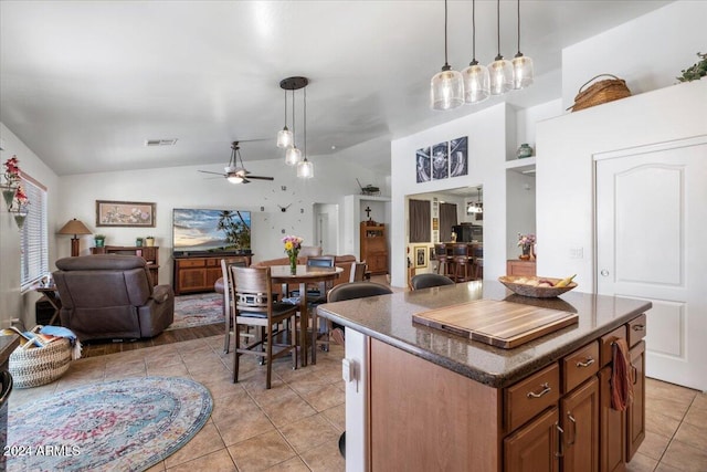 kitchen with ceiling fan, light tile patterned floors, decorative light fixtures, a center island, and lofted ceiling