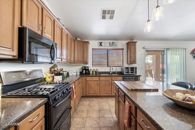 kitchen featuring hanging light fixtures, sink, dark stone counters, and stainless steel appliances