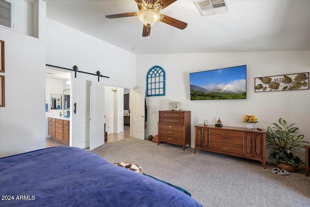 bedroom with connected bathroom, ceiling fan, a barn door, vaulted ceiling, and light carpet