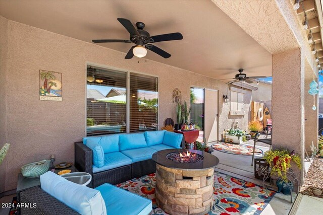 view of patio with ceiling fan and an outdoor living space with a fire pit