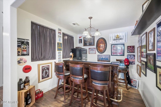 bar featuring dark brown cabinets, dark wood-type flooring, and an inviting chandelier