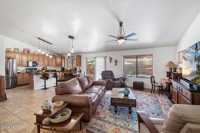 living room with ceiling fan, light tile patterned floors, a wealth of natural light, and vaulted ceiling