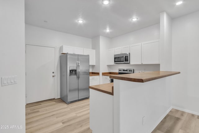 kitchen featuring a peninsula, light wood-style floors, appliances with stainless steel finishes, and white cabinets