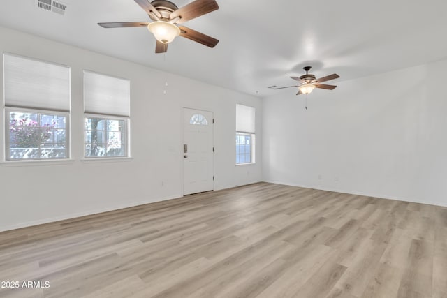 interior space featuring light wood-style floors, baseboards, visible vents, and a ceiling fan