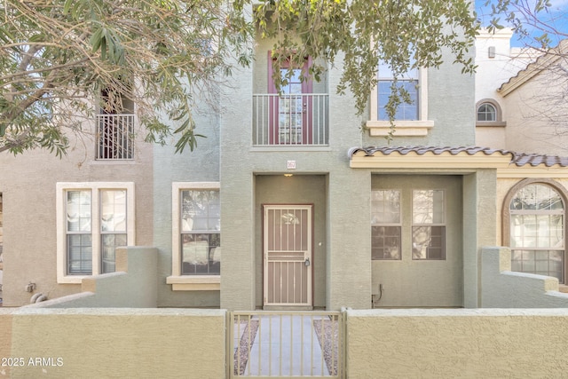 multi unit property with a fenced front yard, a tile roof, and stucco siding