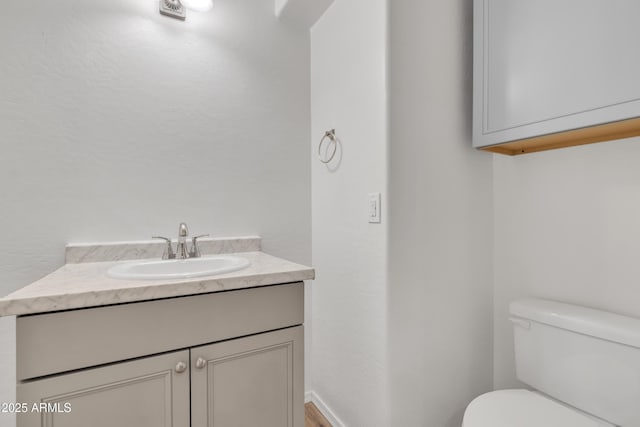 bathroom with baseboards, vanity, and toilet