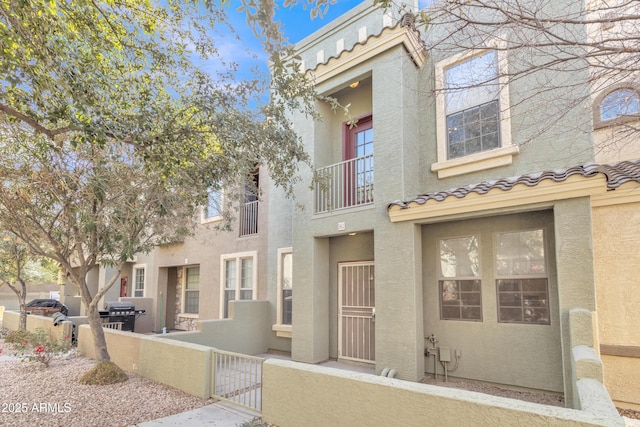 view of front of house with a fenced front yard, a gate, a tiled roof, and stucco siding