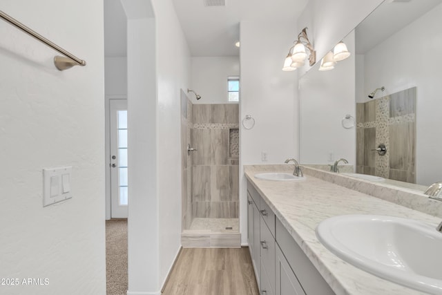 bathroom featuring double vanity, a walk in shower, and a sink