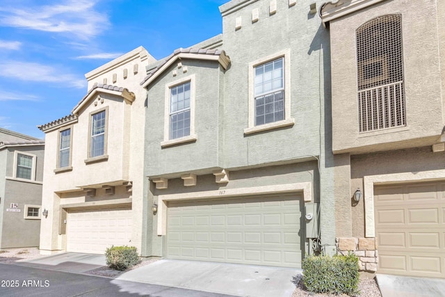 townhome / multi-family property with a garage, a tile roof, and stucco siding