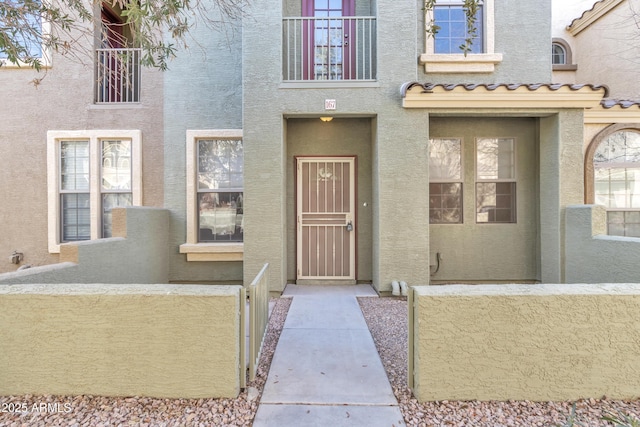 view of exterior entry featuring a tile roof and stucco siding