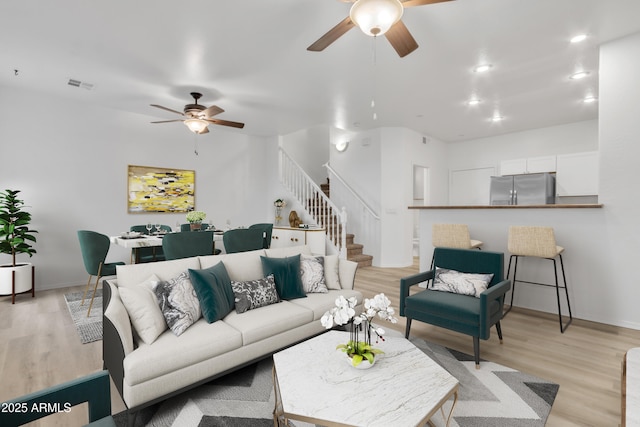 living room featuring visible vents, a ceiling fan, stairs, light wood-type flooring, and recessed lighting