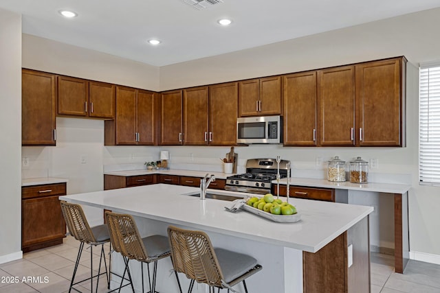 8027 W Northview Ave, Glendale, AZ 85303 - kitchen with stainless steel appliances, light tile patterned flooring, a center island with sink, light countertops, and a kitchen bar