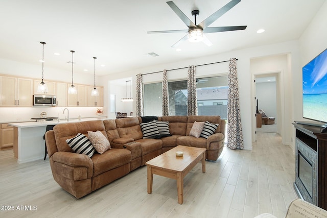 living room with a wealth of natural light, ceiling fan, and light wood-type flooring