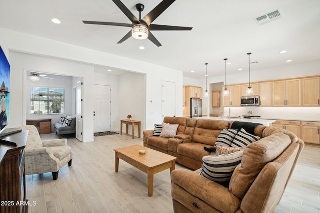 living room with sink, ceiling fan, and light hardwood / wood-style flooring