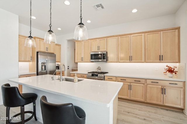 kitchen with stainless steel appliances, hanging light fixtures, sink, and light brown cabinets