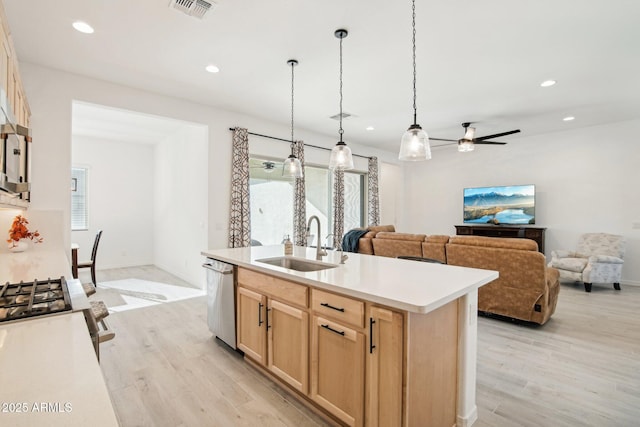 kitchen with pendant lighting, sink, stainless steel appliances, an island with sink, and light brown cabinets