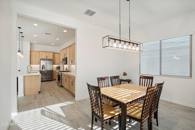 dining area featuring sink and light wood-type flooring