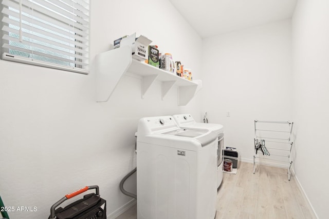 laundry room with washer and dryer and light wood-type flooring